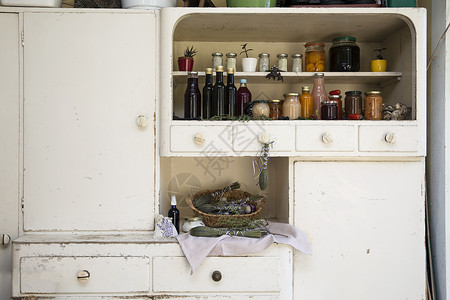 在古老风格厨房橱柜上的罐头和食品瓶子图片