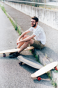 玩滑板的年轻人坐在马路旁休息图片