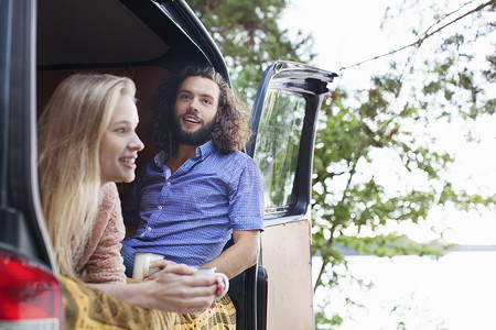 年轻夫妇在湖边的面包车里放松聊天图片