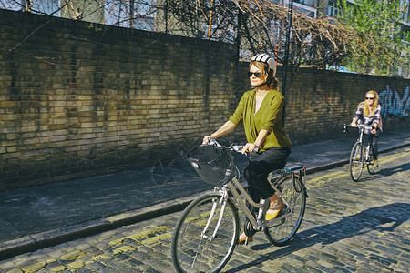 身戴太阳眼镜的妇女将自行车推到路上图片