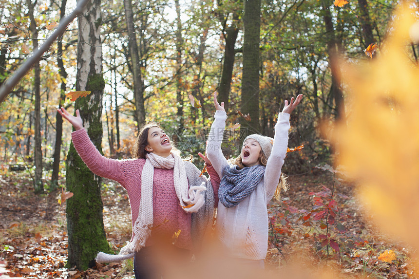 年轻女孩在森林中微笑着举起秋落叶图片