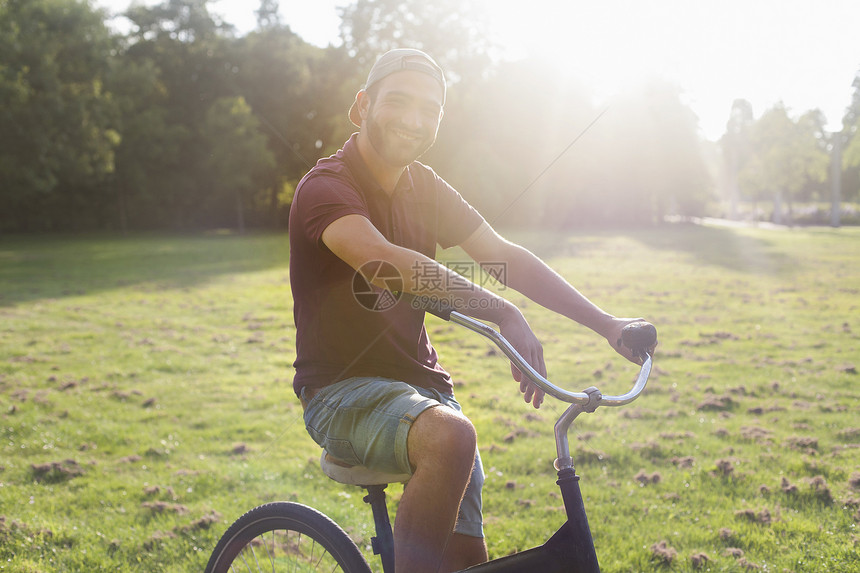 在日光公园骑自行车的青年男子肖像图片