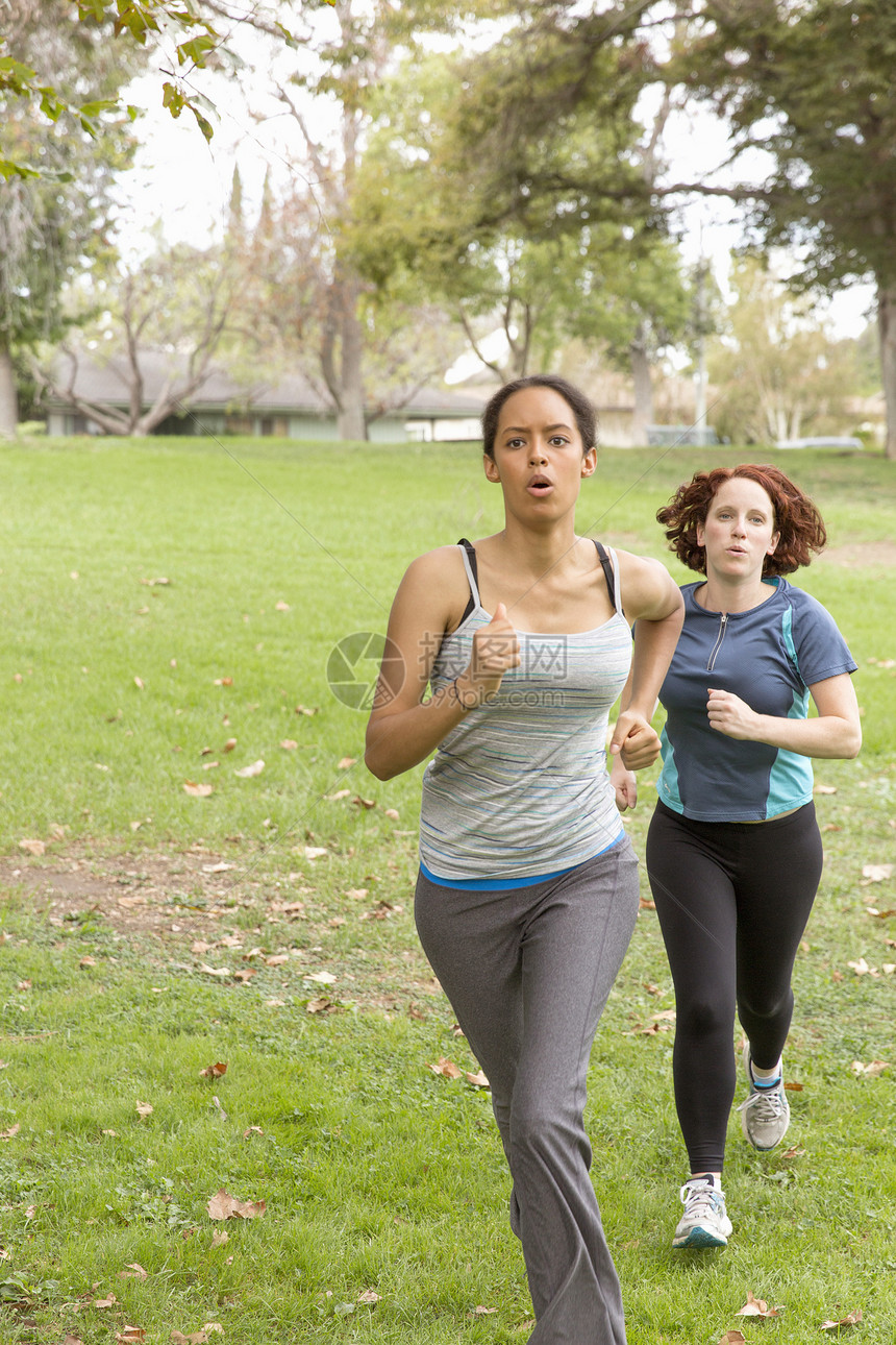 穿着运动服在草地上积极奔跑的妇女图片