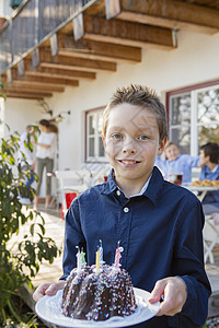 男孩在院子上带着生日蛋糕的肖像图片