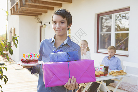 带着生日蛋糕和庭院礼物的十几岁男孩肖像图片
