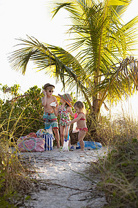 海滩收集贝壳的男孩和两个姐妹背景图片