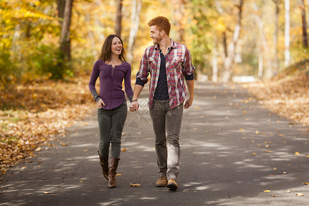 在秋林中漫步的浪漫年轻夫妇高清图片