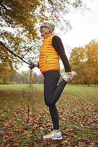 秋季公园穿橙色马甲的成年女子一脚站立拉伸图片