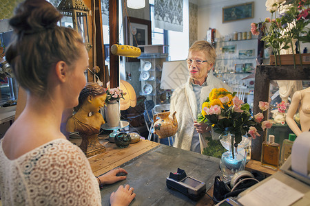 在老店买茶壶的年轻女顾客与女老板背景图片