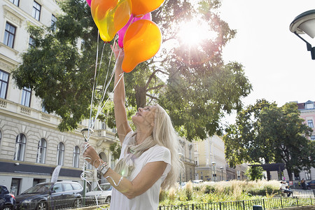 成熟的女人户外拿着一堆气球图片