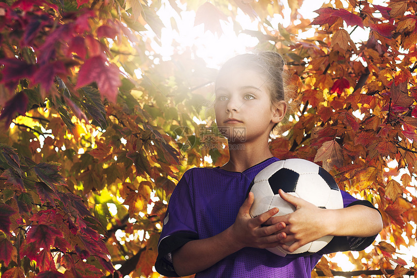 秋天的树叶覆盖着女孩们带着足球向远方看图片