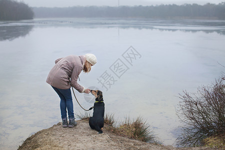 年中成女子在河岸上抚摸她的狗图片