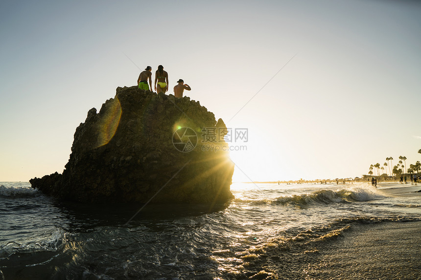 美国加利福尼亚州纽波特海滩日落时岩石形成问题人朋友的轮椅图片
