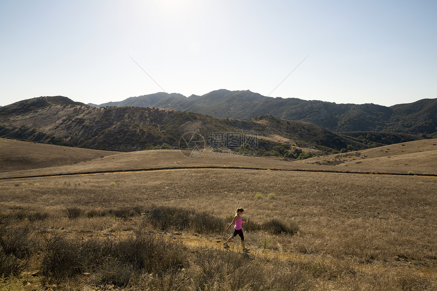 在美国加利福尼亚州千橡树镇穿越地貌的年轻女跑步者图片