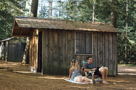 年轻夫妇在森林小屋外放松图片