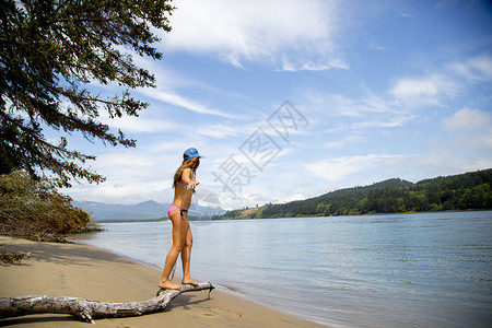 海滩树枝上穿比基尼保持平衡的年轻女子图片