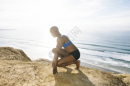 年轻姑娘在海边的岩石上蹲着图片