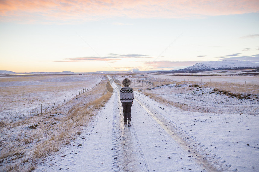 冰岛在雪覆盖的乡村公路上行走的妇女图片