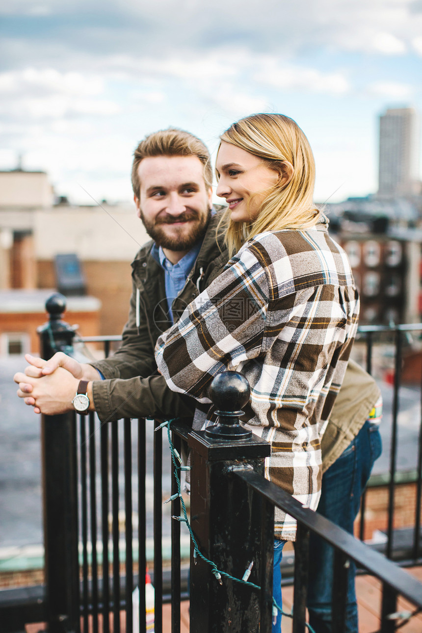 快乐的一对年轻夫妇在城市屋顶露台聊天图片