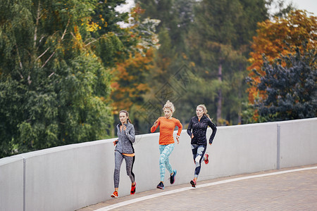 三名女跑者沿公园路图片
