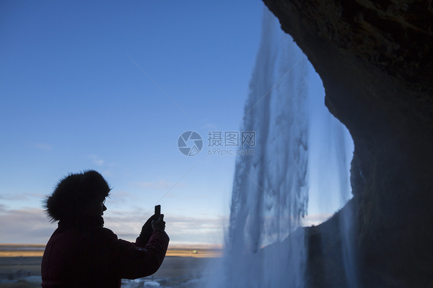 拍摄冰岛西南Seljalandsfos瀑布的妇女照片图片