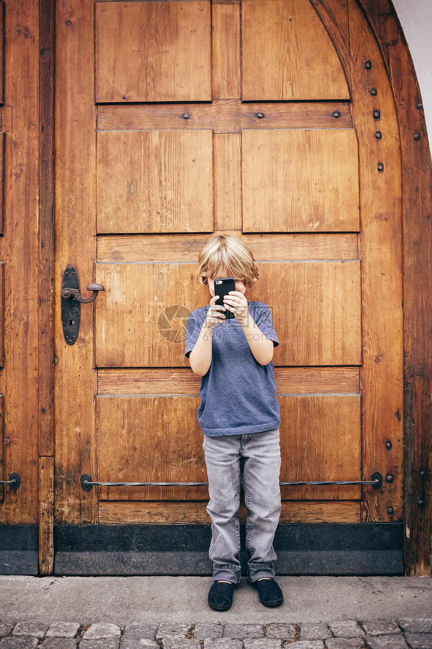 用智能手机拍照的男孩图片