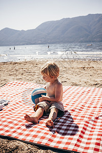 男孩坐在沙滩上图片