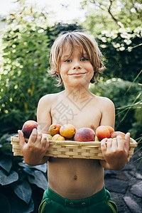 男孩拿着一篮子水果微笑看着镜头图片