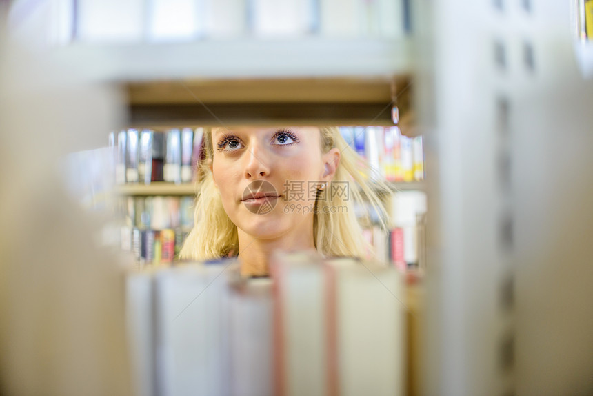在图书馆架后面的年轻女子图片