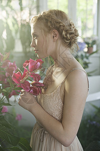 金发年轻女人闻着粉红色花朵香味的肖像图片