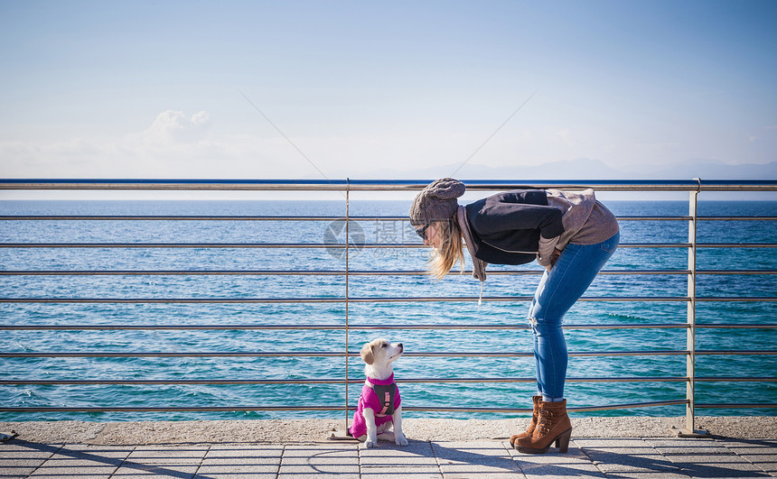 年轻女性在海边逗狗图片
