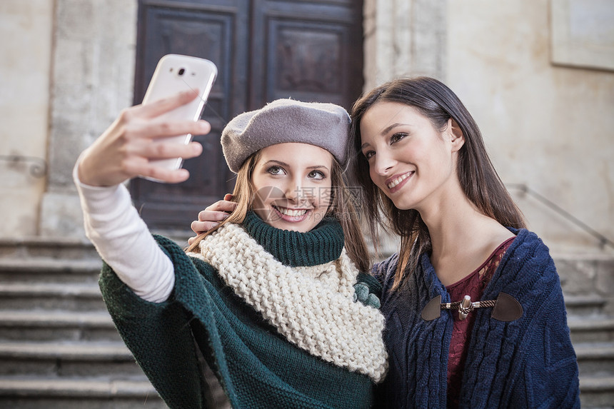 两位年轻女性使用智能手机自拍图片