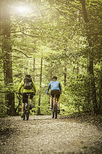 在森林足迹上骑自行车的成熟山骑双车夫妇近视背景图片