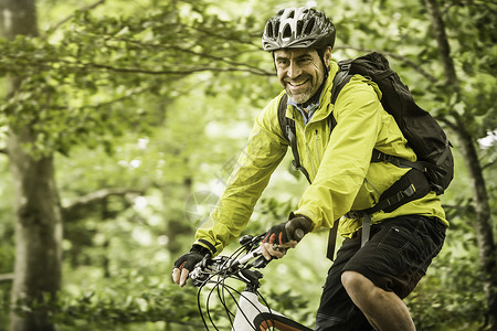 快乐的成熟男山上骑自行车在森林中骑自行车图片