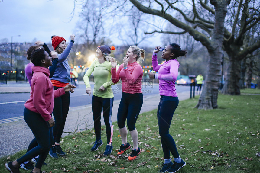 6名成年女跑者在黄昏时城市边缘庆祝图片