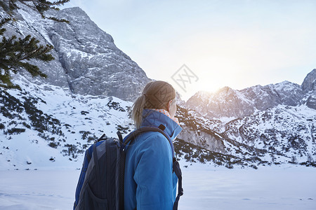 年轻女子在雪中徒步山顶看太阳奥地利图片