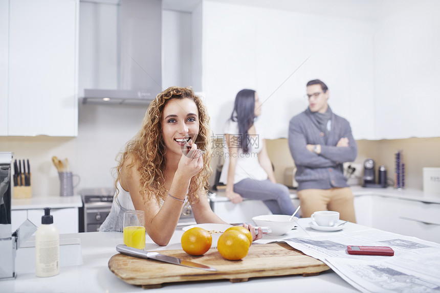 年轻妇女在厨房柜台吃早餐谷类的肖像图片