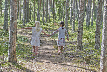 在森林中行走时看到两名女孩身着旧衣服手握图片