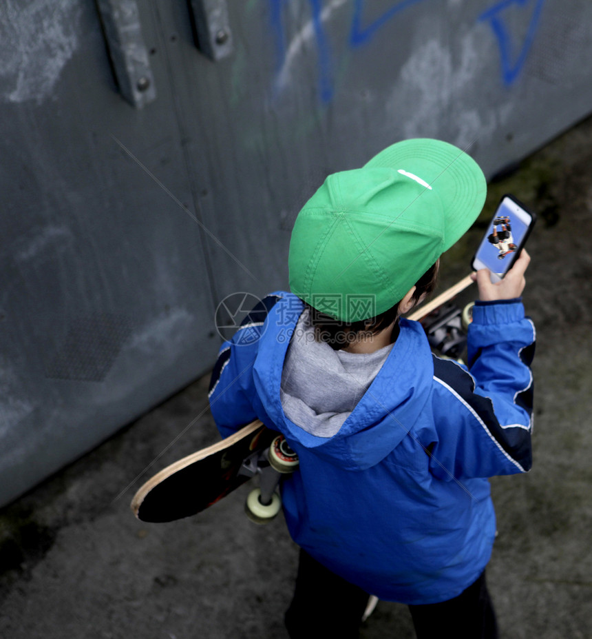 年轻的滑板运动员在看智能手机照片图片
