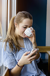 看手机边喝咖啡的年轻女人图片