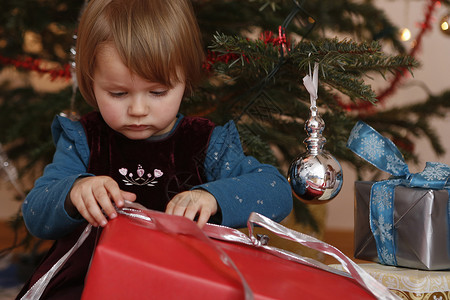 女孩在圣诞树前拆礼物图片