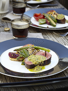 户外木制花园餐桌上的牛肉和烧烤沙拉特写高清图片