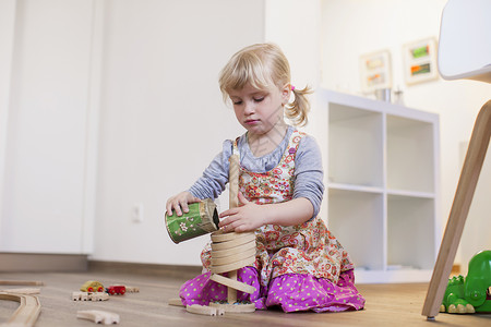 女孩跪在木地板上玩耍玩具图片