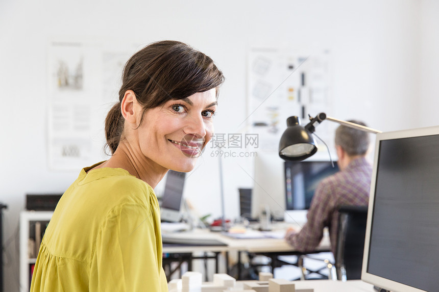 坐在办公室的女人侧头看着镜头微笑图片