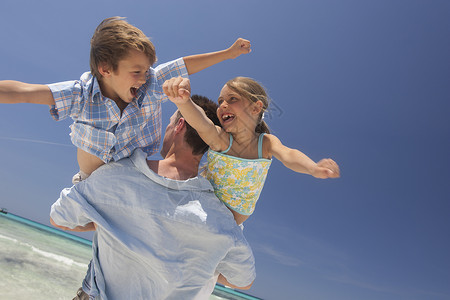 在西班牙海滩抱着儿子和女儿的成年中男子图片