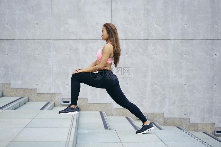 年轻女子在城市楼梯上伸展大腿图片