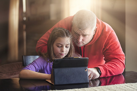 父亲和女儿在家使用无线数字平板电脑图片