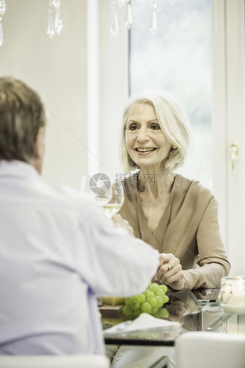 坐在桌边的一对年长夫妇拿着酒杯庆祝图片