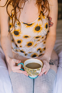 年轻女孩坐在床上拿着茶杯中区图片