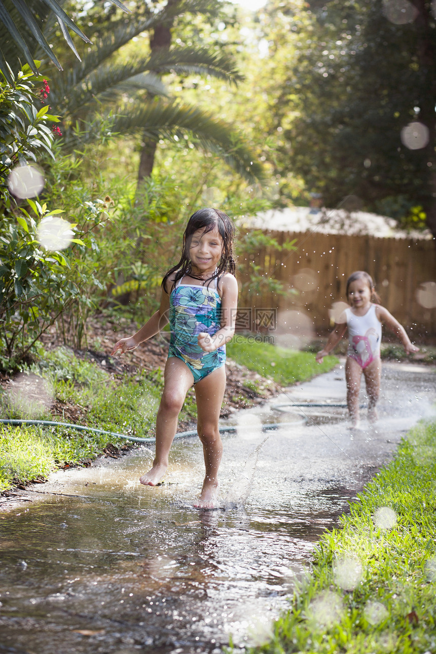 在花园人行道上玩水的女孩图片